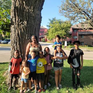 A joyful group of children enjoying a sunny day together near a big tree.