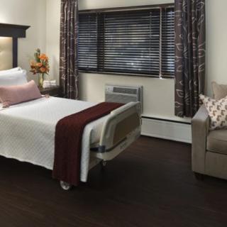 A well-furnished hospital room featuring a bed, sofa, and curtains.