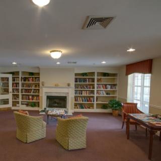 A cozy library room with bookshelves, a fireplace, and comfortable seating.