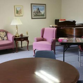 A cozy living room with a piano and pink furniture.