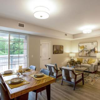 A modern and cozy living room with a connected dining area, featuring stylish furniture and warm lighting.