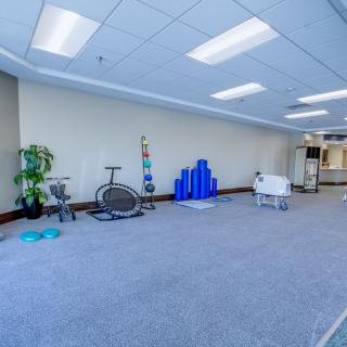 A spacious office area featuring exercise equipment and a modern design with carpeted floors and bright lighting.