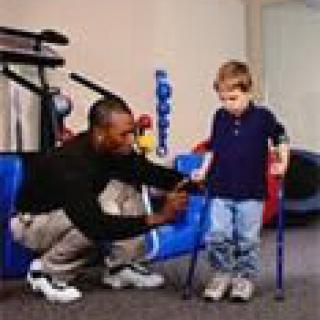 A therapist assists a young child using crutches during a physical therapy session.