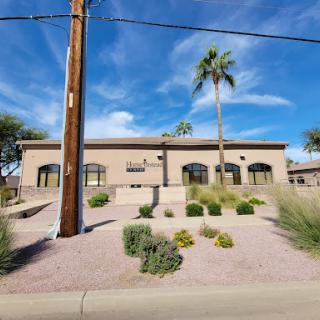 A modern building surrounded by desert landscaping and palm trees under a bright blue sky.