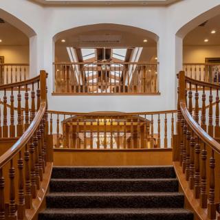 A luxurious interior with a grand wooden staircase and skylights.