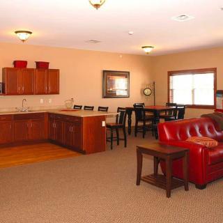A spacious open-concept living area featuring a kitchen, dining table, and red sofa.