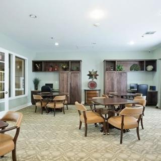 A well-organized meeting room with multiple tables and computer stations, featuring elegant wooden decor.