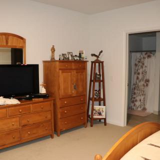 A cozy bedroom featuring wooden furniture, including a dresser with a mirror and a television on top.