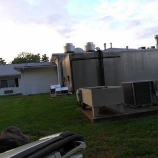 A view of a building's exterior featuring air conditioning units on the side lawn.