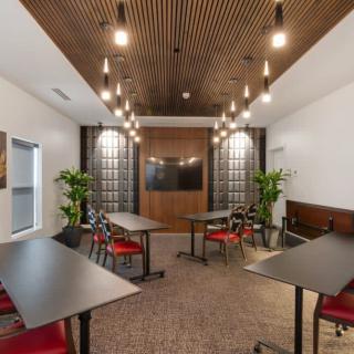 A modern meeting room with sleek tables and chairs, stylish lighting, and decorative plants.