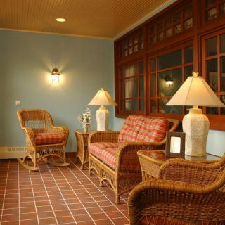 A cozy sunroom with wicker furniture and warm lighting.