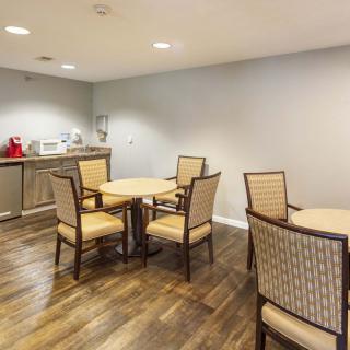 A small conference room with tables, chairs, and a kitchenette equipped with a microwave and coffee maker.