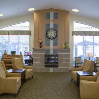 A cozy living room featuring a central fireplace, surrounded by comfortable seating and large windows.