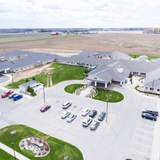 Aerial view of a building complex with a parking lot surrounded by open fields.
