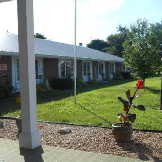 A cozy motel surrounded by well-maintained lawns and colorful plants under a clear blue sky.