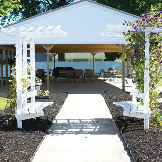 A beautifully landscaped garden area with a pergola and benches leading to a gazebo.