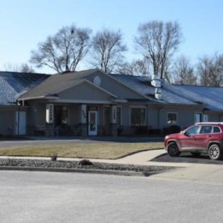 A suburban house with a red SUV parked in the driveway on a clear day.
