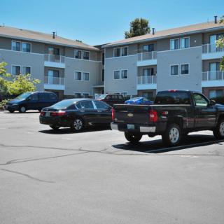 Cars parked in front of an apartment complex on a sunny day.