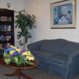 A cozy living room with a blue sofa, bookshelf, and a coffee table adorned with colorful flowers.