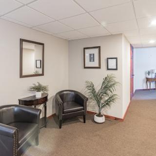A modern office waiting area featuring comfortable chairs, decorative plants, and framed art.