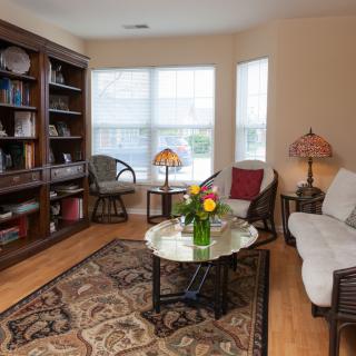 Cozy living room with a bookshelf, sofa, and coffee table adorned with flowers.