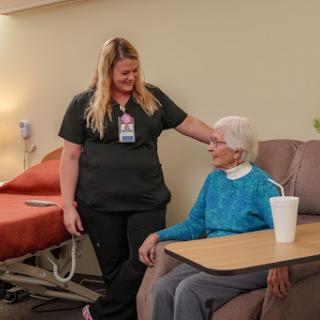 A caregiver interacts warmly with an elderly resident in a healthcare setting.
