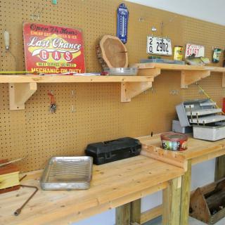 A well-organized workshop featuring tools and vintage signs displayed on a pegboard with wooden shelves.