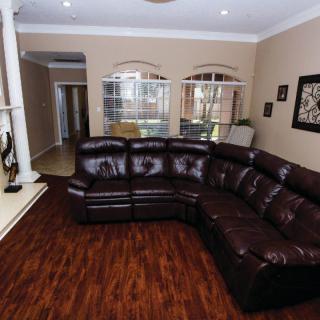A cozy living room with a dark leather sectional sofa and hardwood flooring.