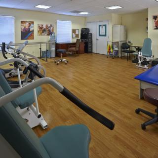 A well-equipped physical therapy room with various exercise machines and rehabilitation tools.