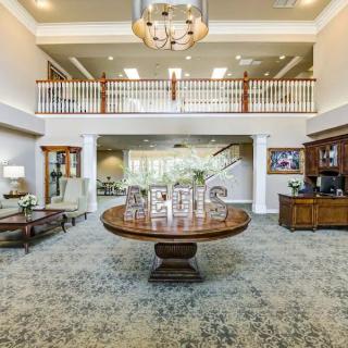 A luxurious lobby with elegant decor, featuring a central round table, chandelier, and stylish furnishings.