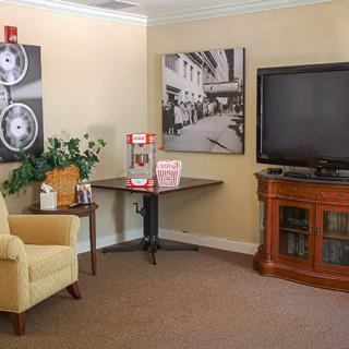 A cozy living room featuring a TV, popcorn machine, and comfortable seating.