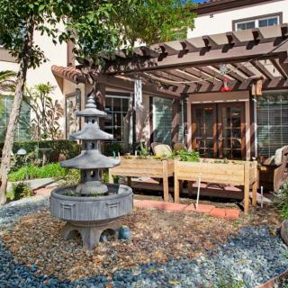 A beautifully landscaped garden with a fountain and pergola-covered patio area.