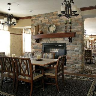 A cozy dining room featuring a stone fireplace and wooden furniture.