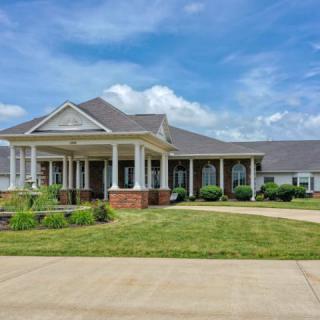A spacious suburban house with a well-maintained lawn and a clear blue sky.