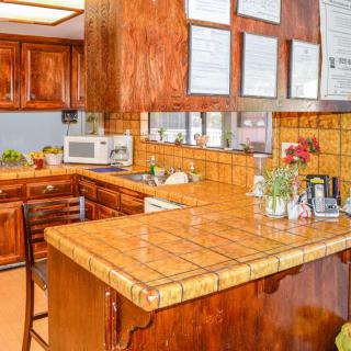 A cozy kitchen featuring wooden cabinets and a tiled countertop, complete with appliances and decorative plants.