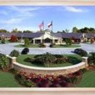 A landscaped entrance with a building in the background, featuring flags and a circular driveway.