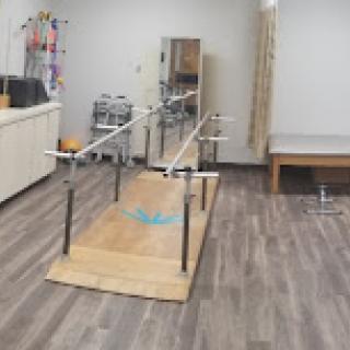 A physical therapy room equipped with parallel bars for rehabilitation exercises.