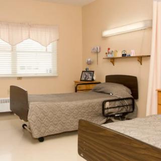 A clean and well-organized healthcare facility room with two beds and essential amenities.