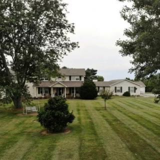 A suburban house with a well-maintained lawn and surrounding trees.