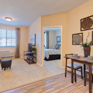 A modern apartment featuring a cozy living room with a view into the bedroom and an adjacent dining area.