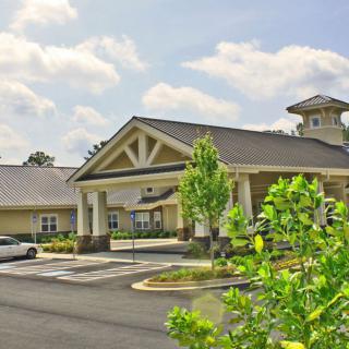 A suburban building with a parking lot and greenery on a cloudy day.