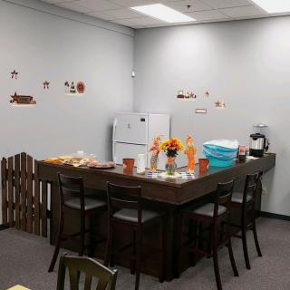 A cozy breakroom with a table, chairs, and festive decorations.
