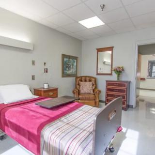 A clean and well-furnished hospital room with a bed and chair.