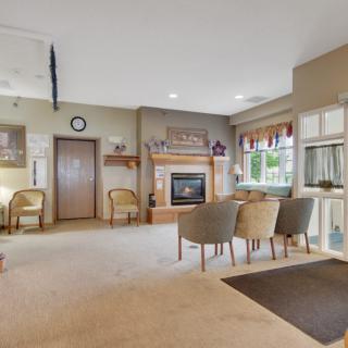 A cozy living room with a fireplace, seating area, and natural lighting.