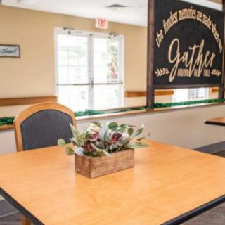 A cozy restaurant interior with a wooden table, chairs, and decorative plants.
