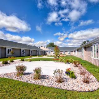 A beautifully landscaped courtyard surrounded by residential buildings under a blue, partly cloudy sky.