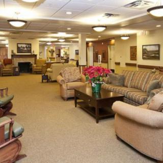 A spacious lobby with comfortable seating, including sofas and armchairs, centered around a coffee table, with warm lighting overhead.