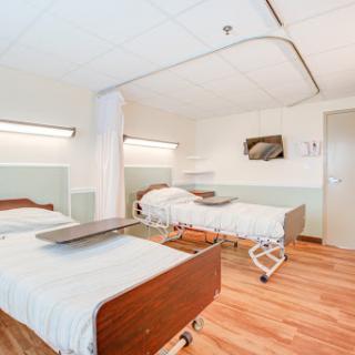 A modern and clean hospital patient room featuring two adjustable beds.