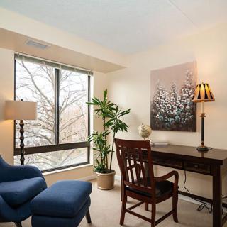 A cozy office space with a wooden desk, comfortable chairs, and a large window providing natural light.