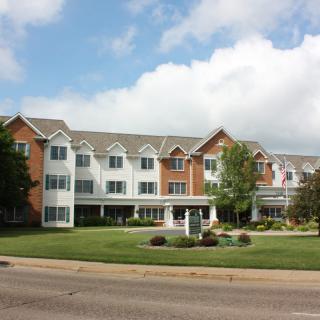 A three-story residential building with a landscaped lawn and trees.